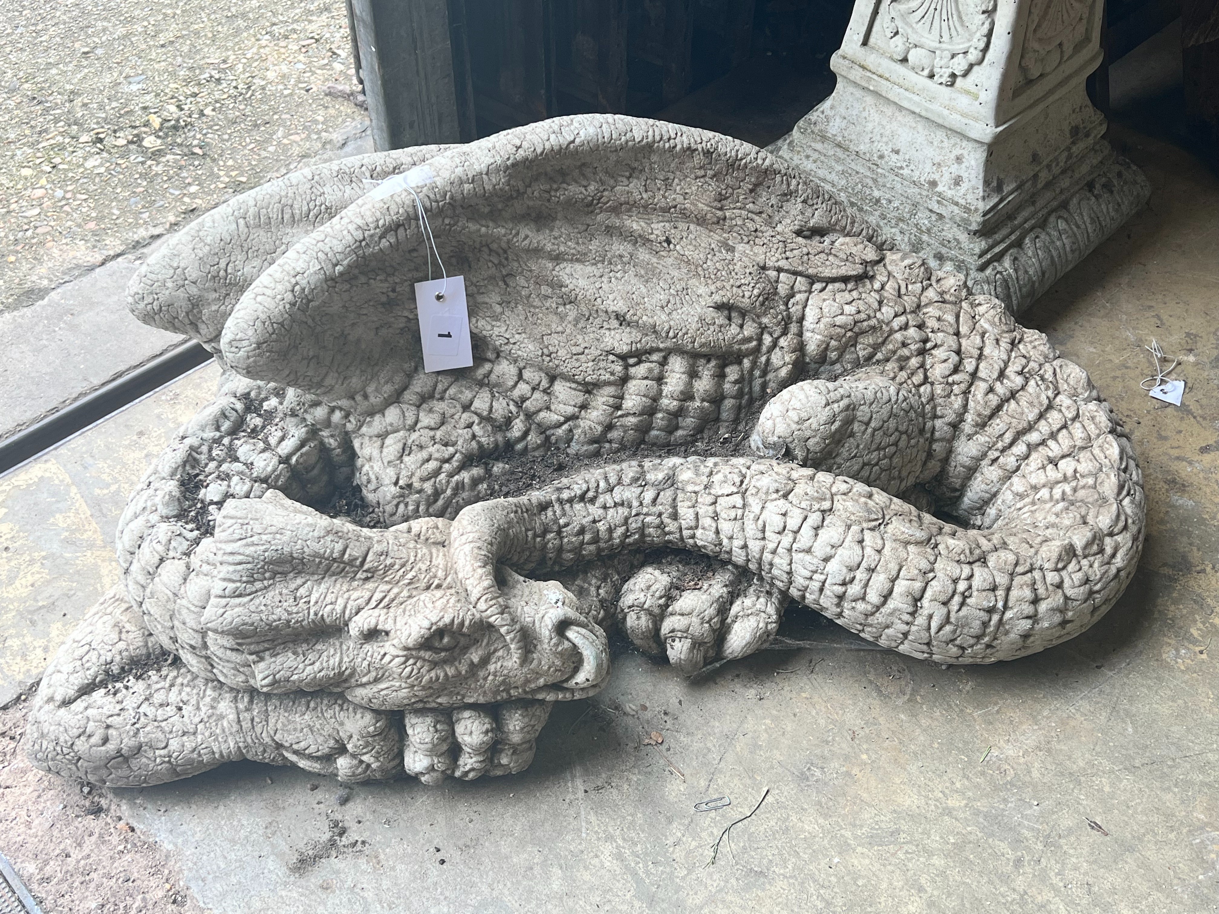 A reconstituted stone garden ornament of a sleeping dragon, width 80cm